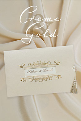 Cremefarbene, schillernde Hochzeitseinladung mit gestanztem Sichtfenster und goldenen, geprägten Blumenranken. Angeknüpfte, goldene Quaste