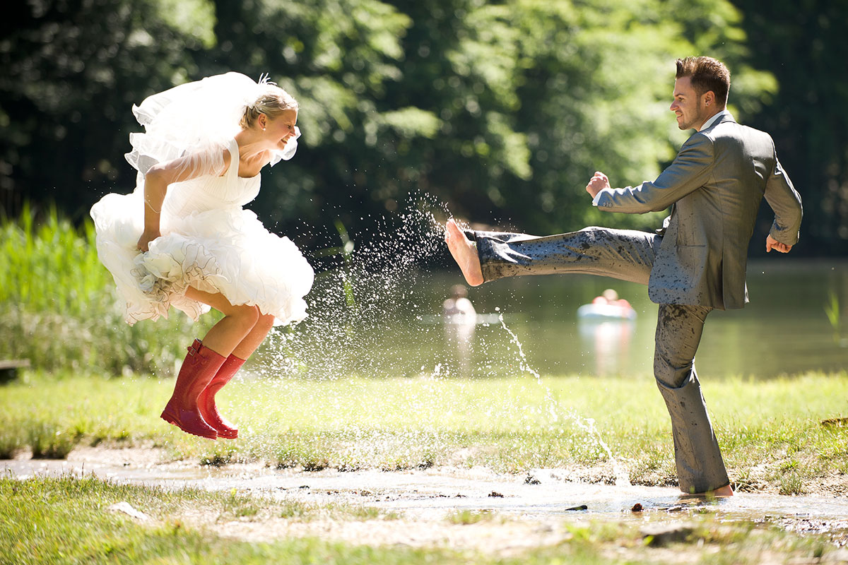 Braut und Bräutigam spielen im Wasser.